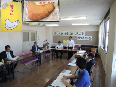 起立して総会を進行させる議長。史料寄付者から鎌倉名物鳩サブレーも贈られてきた