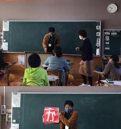 写真上は教壇前で担任の先生と事務局瀬戸が会話している。写真下は事務局瀬戸が音次郎かるたの作品発表で「か」の文字札を持っている。