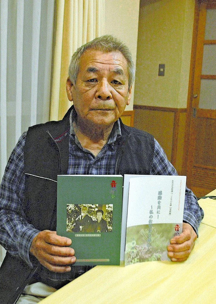 完成した「感動を共に！～私の音次郎伝～」の本を両手で持ち、こちらを見つめる著者の中平菊美会長