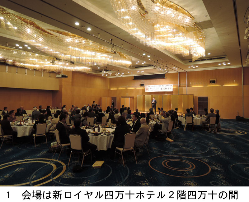 会場となった新ロイヤル四万十ホテル２階の四万十の間。後方から前方の舞台を眺める。舞台後ろには金屏風。その上には出版祝賀会を知らせる看板が吊り下げられている。壇上には四万十市長が